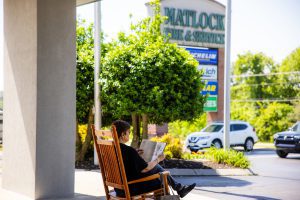 woman reading and rocking on front porch of matlock tire service